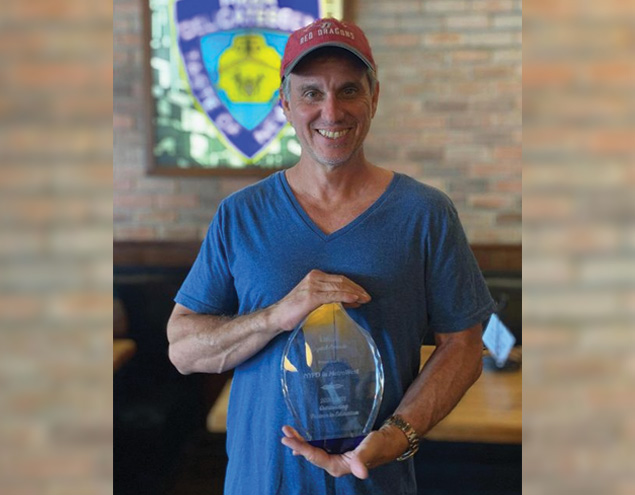 Image of NYPD Pizza founder and CEO Paul Russo holding an OCPS West Learning Community Award