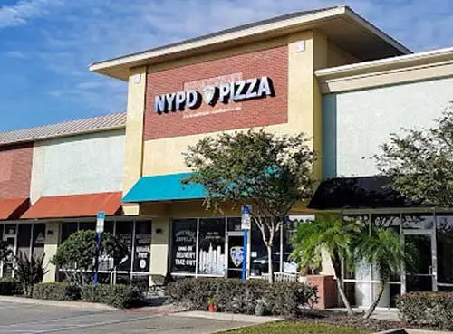 The NYPD Pizza Winter Garden restaurant with a beige and red façade, front windows displaying graphics, and small trees along the walkway.